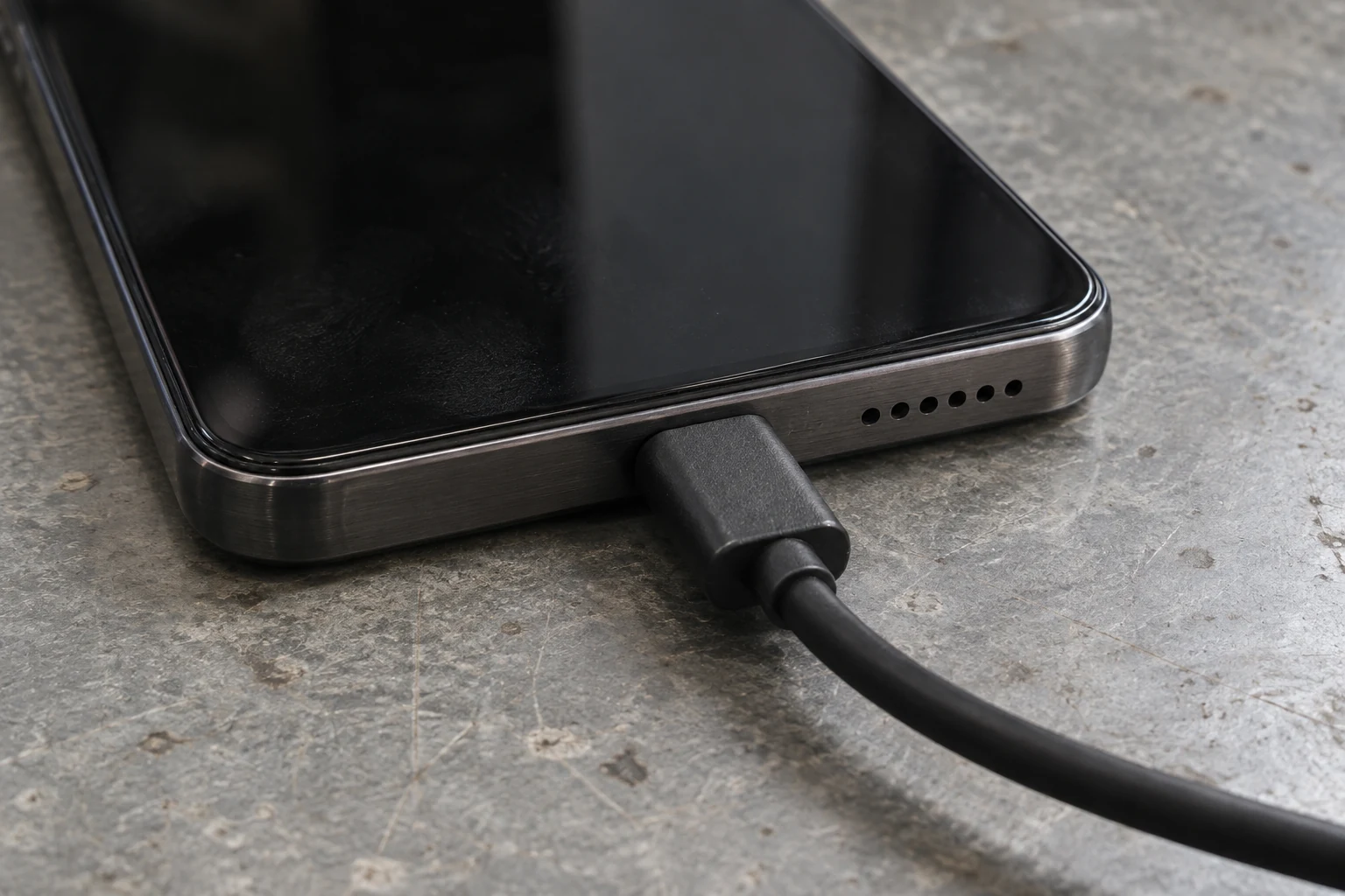 Close view of a USB-C cable seated in the bottom edge of a dark smartphone